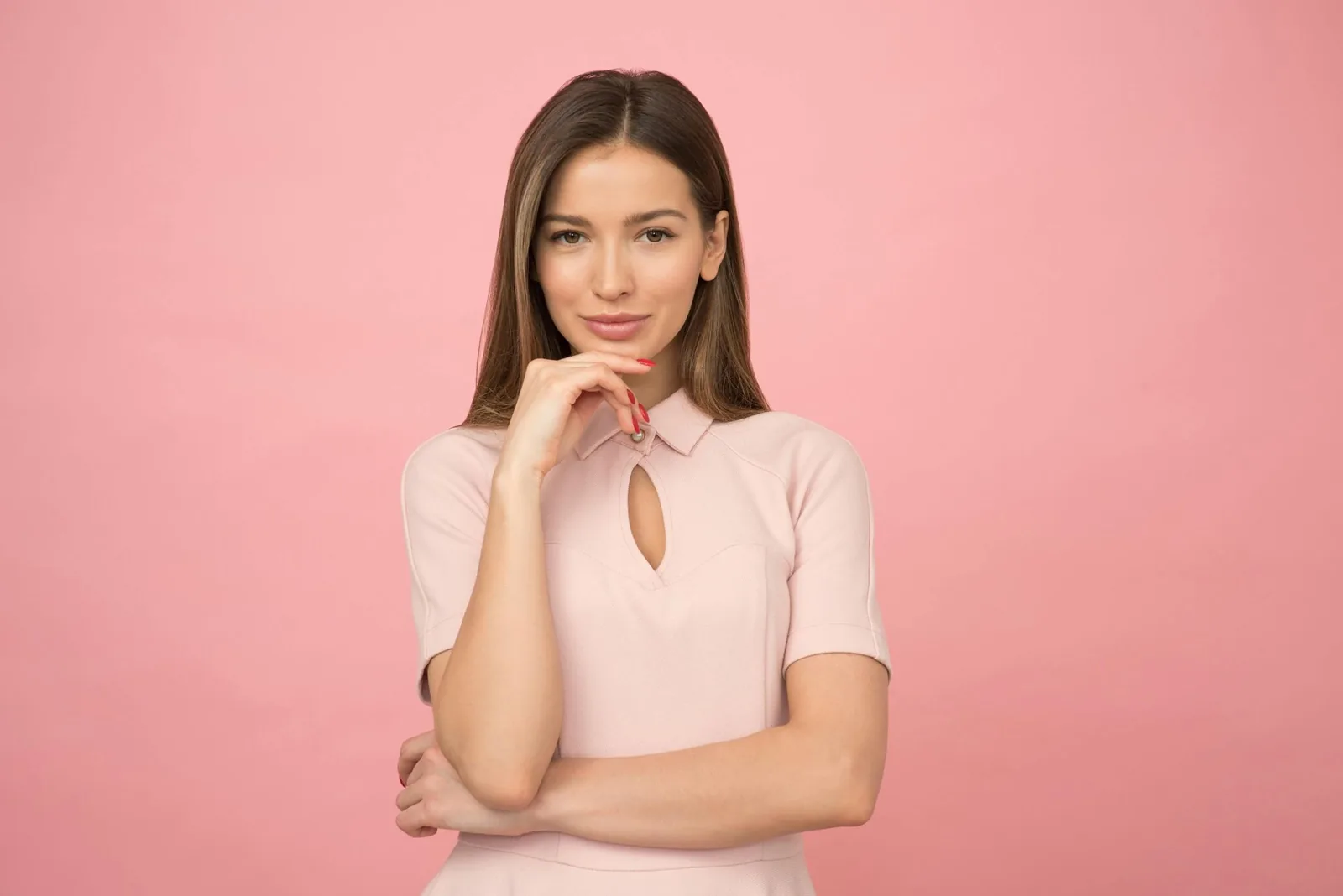 A smiling woman with dark hair in a pink top against a pink background.